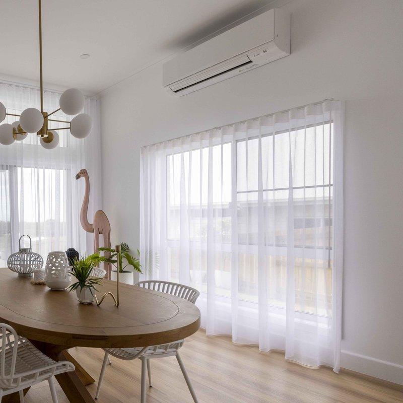 Sheer wave curtains drawn across a bright dining room window