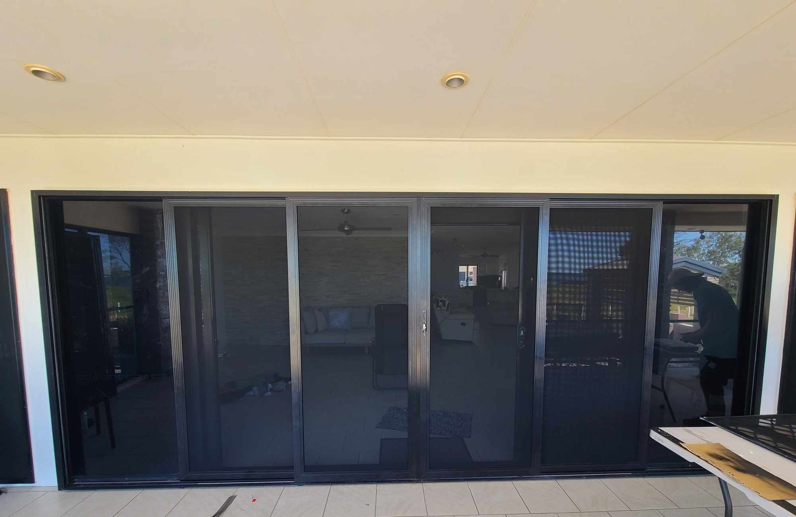 Four black framed sliding security screens across a wall of glass doors, seen from inside