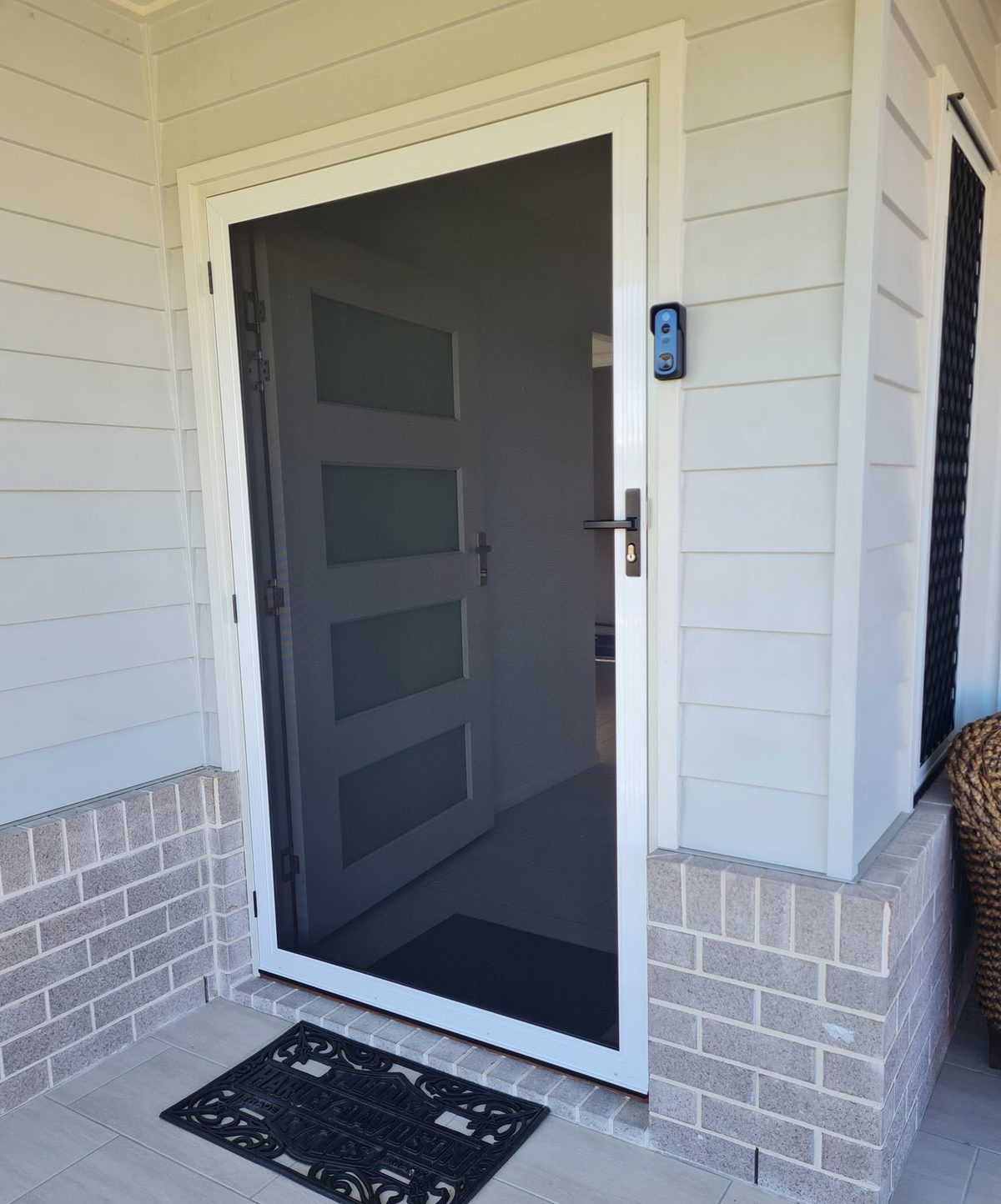 Dark hinged security door over a glazed front door on a brick home