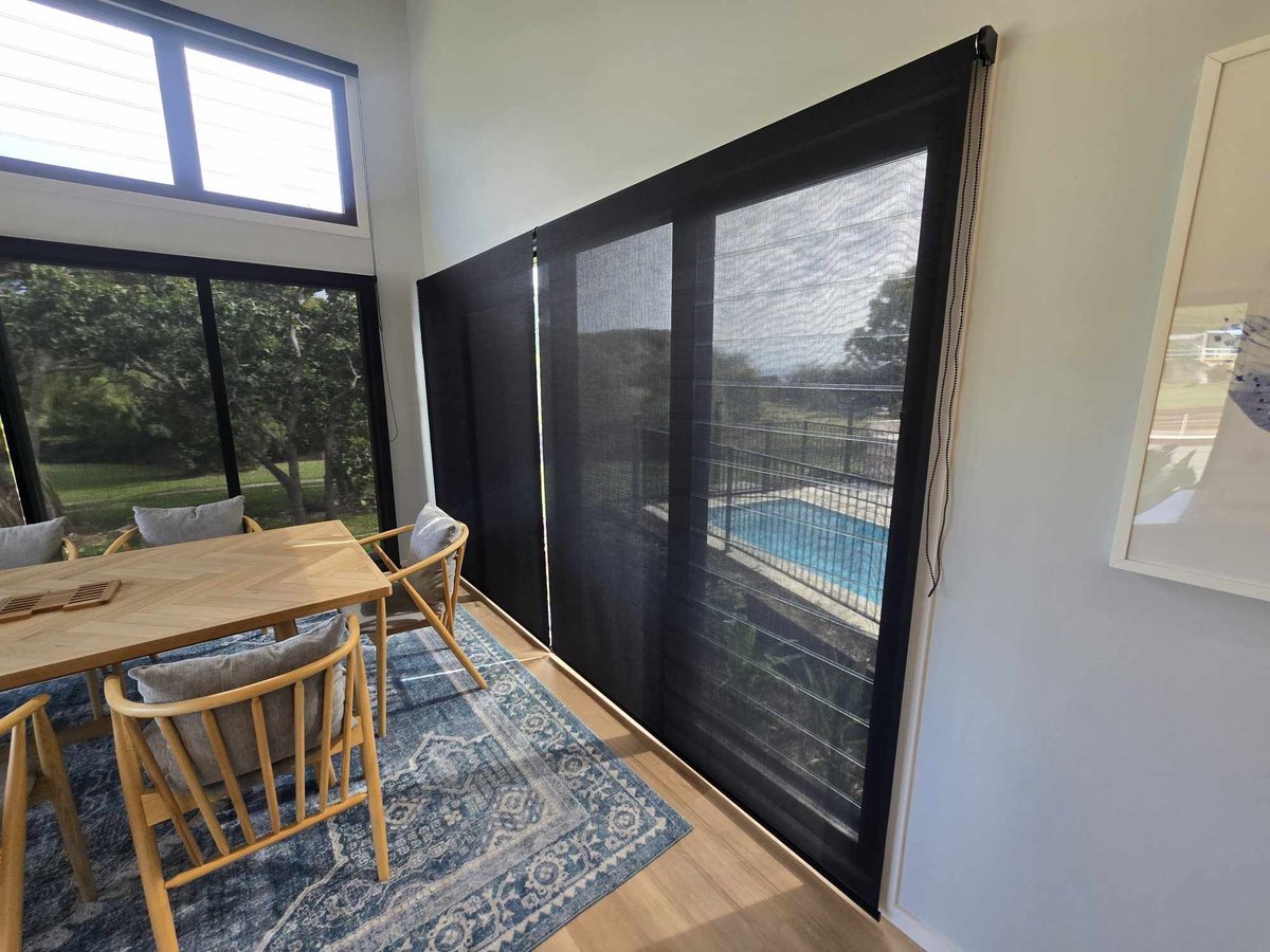 Black framed sliding security screen door in a dining room, with the pool visible through the mesh